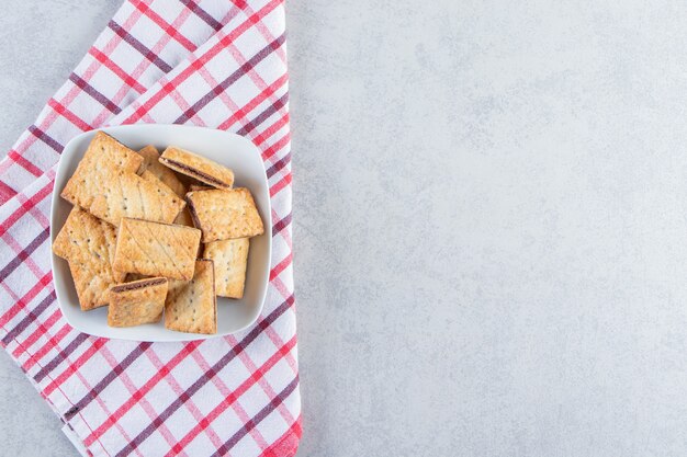 Tazón de fuente blanco de sabrosas galletas crujientes en piedra.