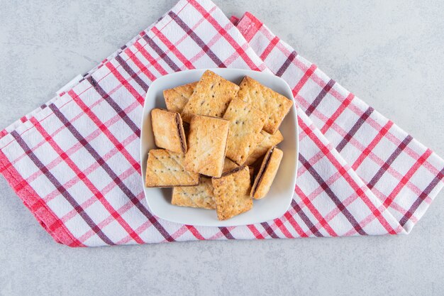 Tazón de fuente blanco de sabrosas galletas crujientes sobre fondo de piedra.