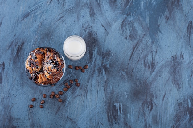 Tazón de fuente de delicioso pastel de canela y vaso de leche en mármol.