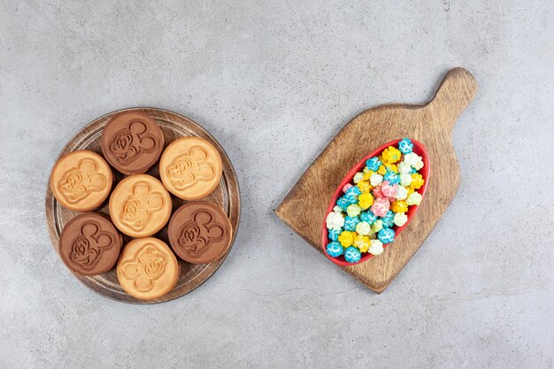Tazón de fuente de dulces de palomitas de maíz y galletas decoradas en bandeja de madera sobre fondo de mármol. Foto de alta calidad