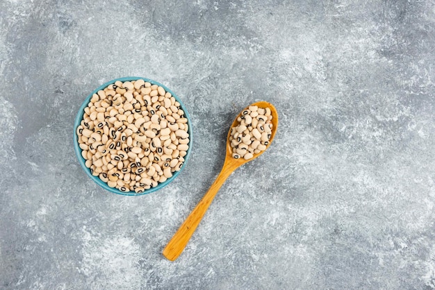 Tazón de fuente de frijoles blancos con cuchara sobre la mesa de mármol.