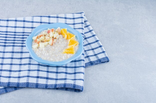 Tazón de fuente con fruta de avena recién cocida sobre fondo de mármol.