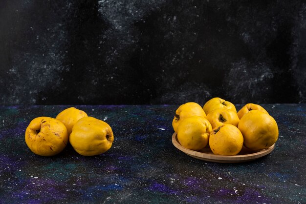 Tazón de fuente de frutos de membrillo maduros colocados sobre la mesa oscura.