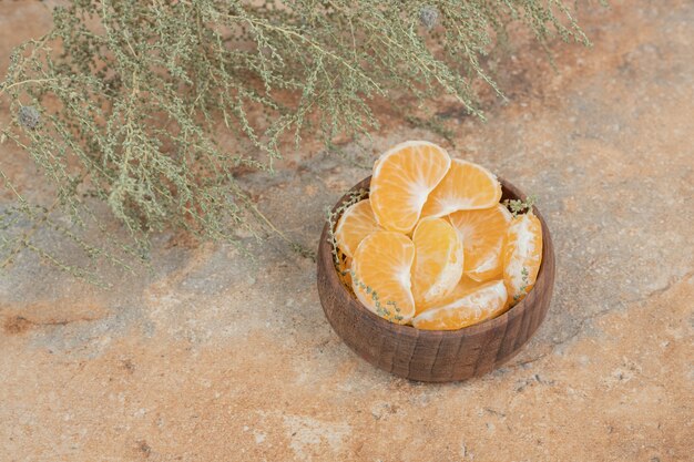 Tazón de fuente de gajos de mandarina fresca sobre fondo de mármol.
