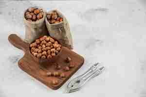 Foto gratuita tazón de fuente de granos de avellana orgánica sobre tabla de cortar con avellanas sin cáscara.