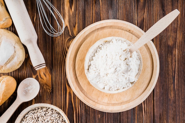 Tazón de fuente de harina blanca en plato de madera sobre la mesa