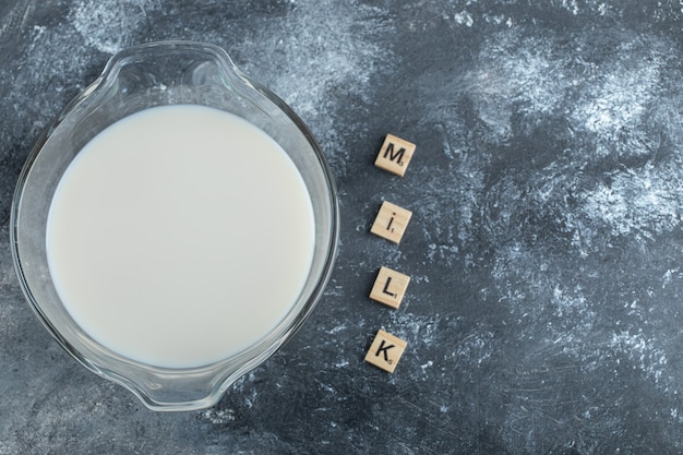 Tazón de fuente de leche y letras de madera deletreadas como leche.