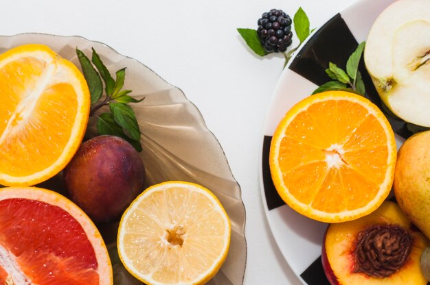 Tazón de fuente y placas de frutas coloridas aisladas sobre fondo blanco