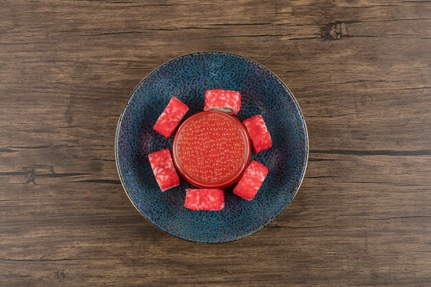 Tazón de fuente de rollos de sushi y caviar rojo sobre mesa de madera