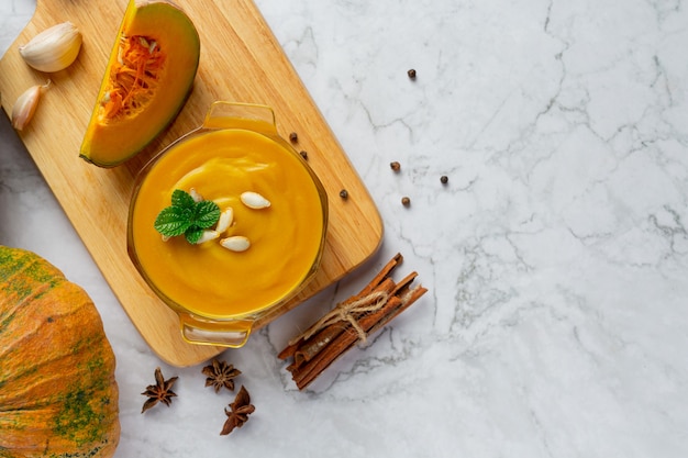 Foto gratuita tazón de fuente de sopa de calabaza en la tabla de cortar de madera