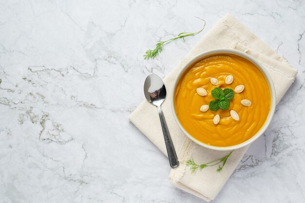 Tazón de fuente de sopa de calabaza en tela blanca