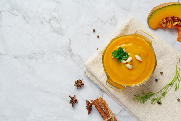 Tazón de fuente de sopa de calabaza en tela blanca