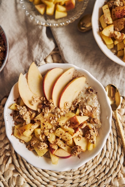 Tazón de gachas de avena con cereales y nueces y rodajas de manzana sobre una mesa