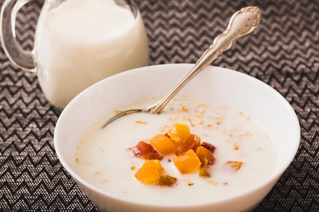 Tazón de leche con ingredientes de frutas sobre mantel