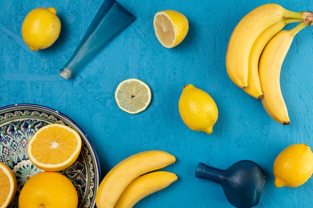 Tazón de limones y plátano sobre fondo azul.