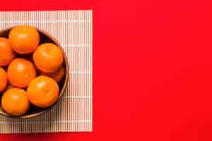 Foto gratuita tazón con mandarinas en la servilleta de bambú