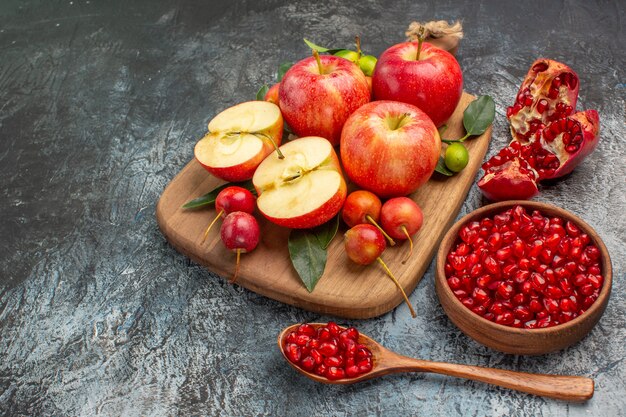 tazón de manzanas de granada manzanas cerezas en la tabla de cortar