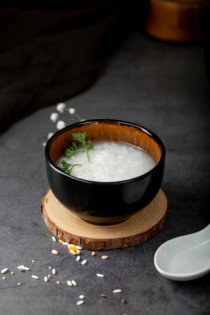 Tazón negro con sopa de arroz sobre un soporte de madera