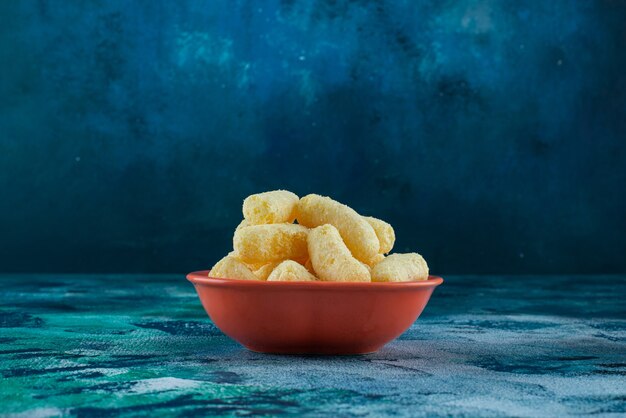 Un tazón de palitos de maíz sabroso en azul.