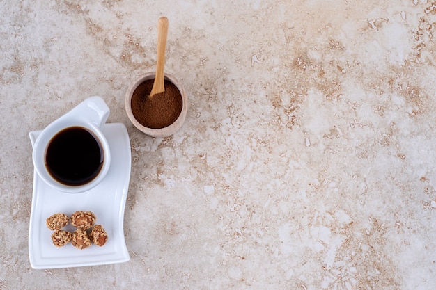 Foto gratuita un tazón pequeño de café molido en polvo, una taza de café y maní glaseado.