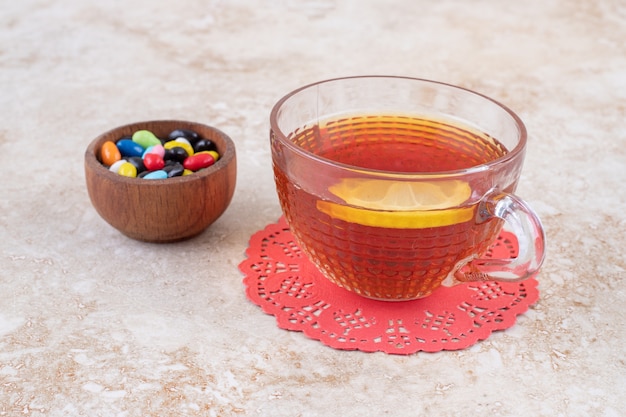 Un tazón pequeño de dulces variados y una taza de té.