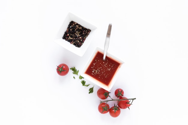 Foto gratuita tazón de pimienta negra y salsa de tomate aislados en superficie blanca