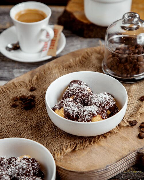 tazón de profiteroles con salsa de chocolate y chispas de coco