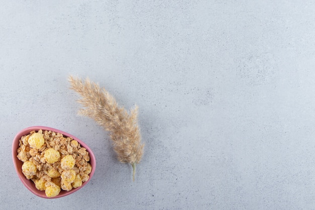 Foto gratuita un tazón profundo de color rosa de deliciosos cereales saludables sobre la superficie gris