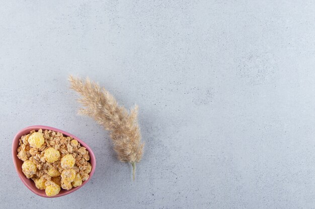 Un tazón profundo de color rosa de deliciosos cereales saludables sobre la superficie gris