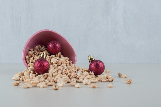 Un tazón rosa lleno de cereales saludables con bolas de Navidad.