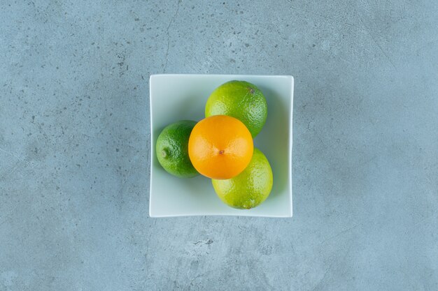 Un tazón de sabrosos limones, sobre el fondo de mármol. Foto de alta calidad