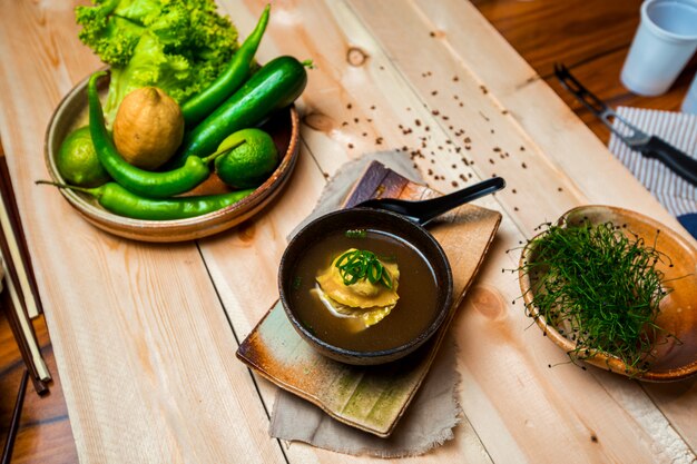 Un tazón de sopa de albóndigas japonesas, plato de verduras y frutas y tazón de hierbas