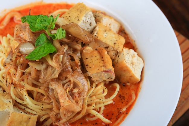 Tazón de sopa blanco con espaguetis y trozos de pan decorados con verduras