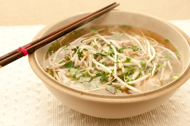 Tazón de sopa pho con caldo, fideos de arroz, hierbas y carne