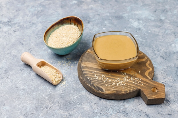 Foto gratuita tazón de tahini con semillas de sésamo sobre superficie de hormigón