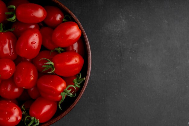 Tazón de tomates en el lado izquierdo sobre fondo negro