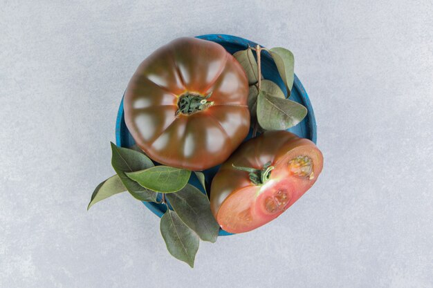 Un tazón de tomates maduros en la superficie de mármol