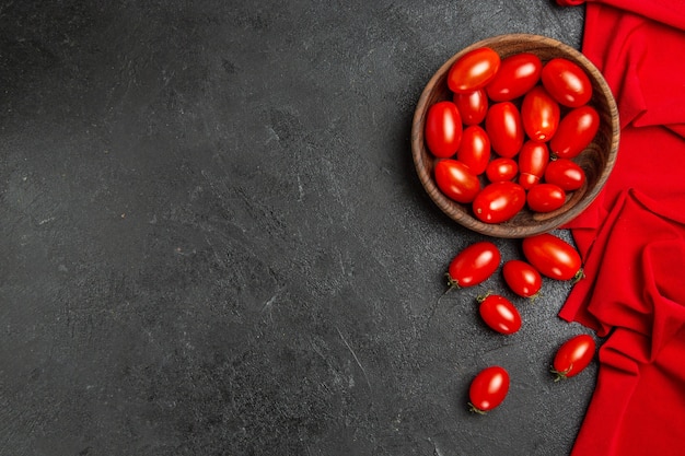 Tazón de vista inferior con tomates cherry toalla roja y tomates cherry sobre fondo oscuro