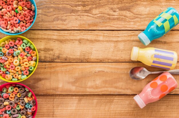 Tazones de cereales con botellas y cuchara en mesa