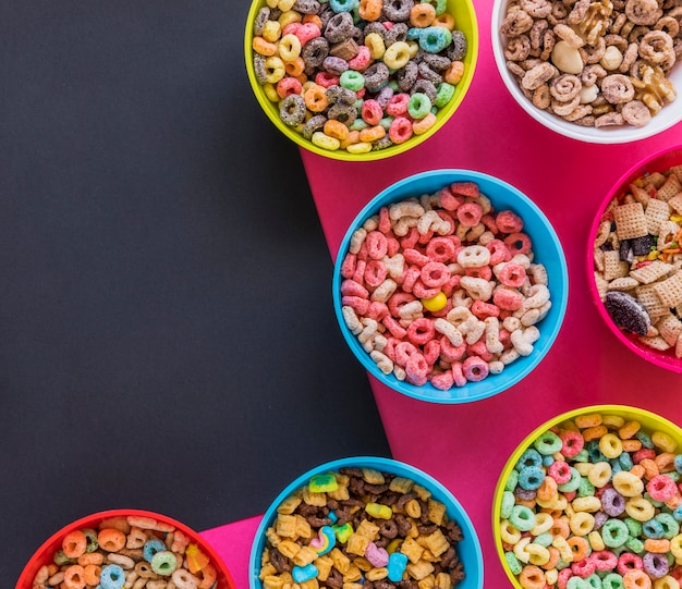 Tazones con diferentes cereales en mesa brillante.