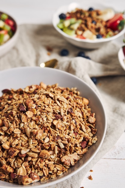 Tazones de granola con yogur, frutas y bayas sobre una superficie blanca