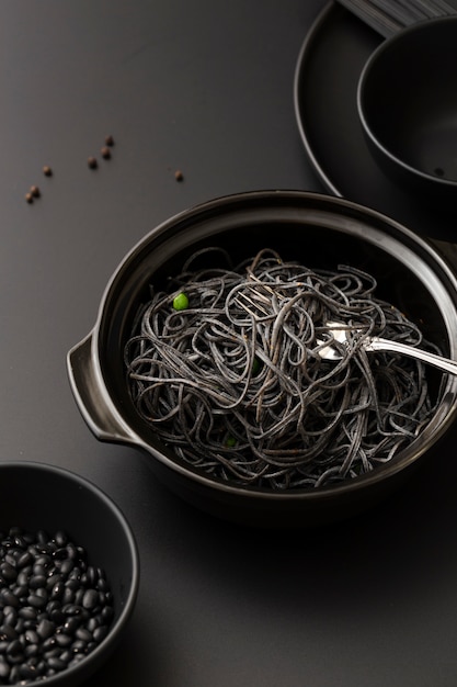 Tazones con pasta oscura y frijoles en una mesa oscura