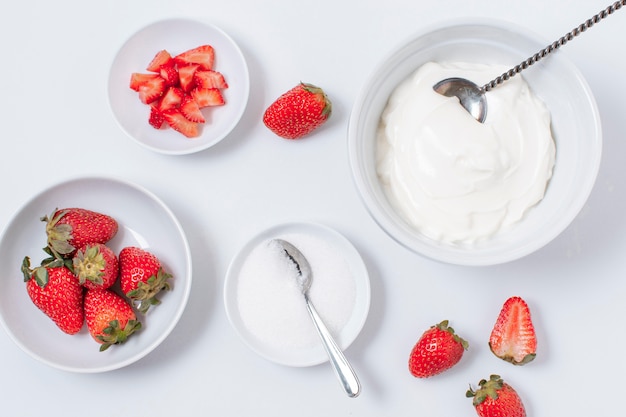 Tazones de yogur de vista superior con fresas sobre la mesa