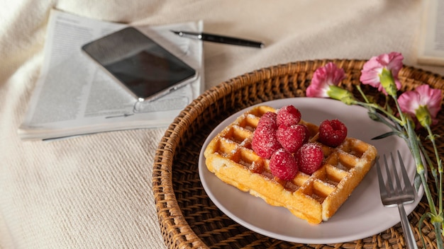 Té de alto ángulo y gofre con frambuesa