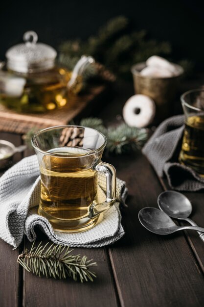 Té de alto ángulo en vaso con ramas de pino