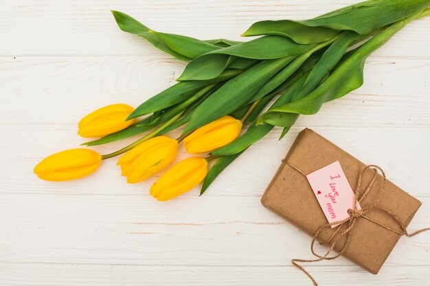 Te amo mamá inscripción con regalo y tulipanes amarillos.