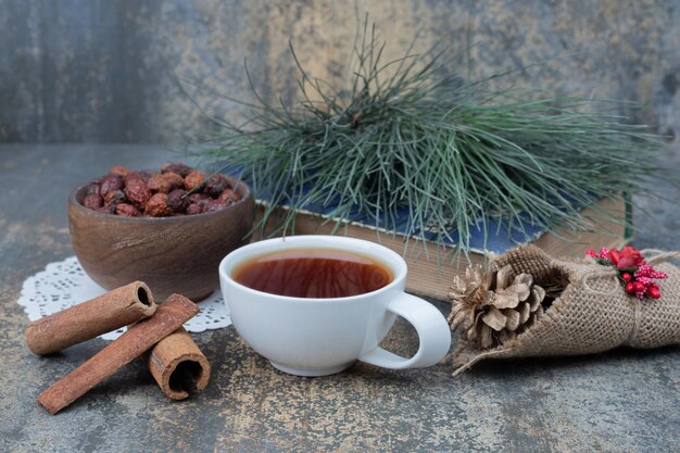 Té aromático en taza blanca con canela y piña en mesa de mármol