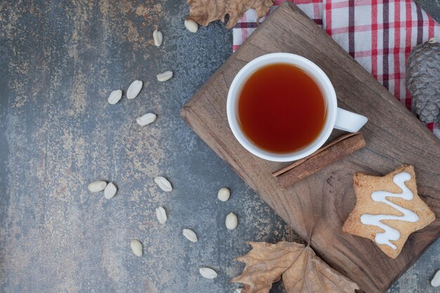 Té aromático en taza blanca con galletas y canela sobre fondo de mármol