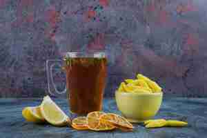 Foto gratuita té caliente con limones y tazón de fuente amarillo de caramelos amarillos sobre fondo azul.