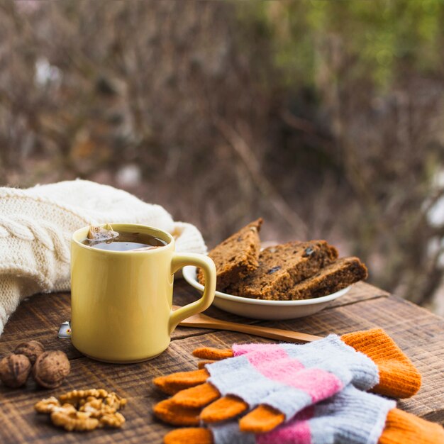 Té caliente y postre cerca de suéter y guantes